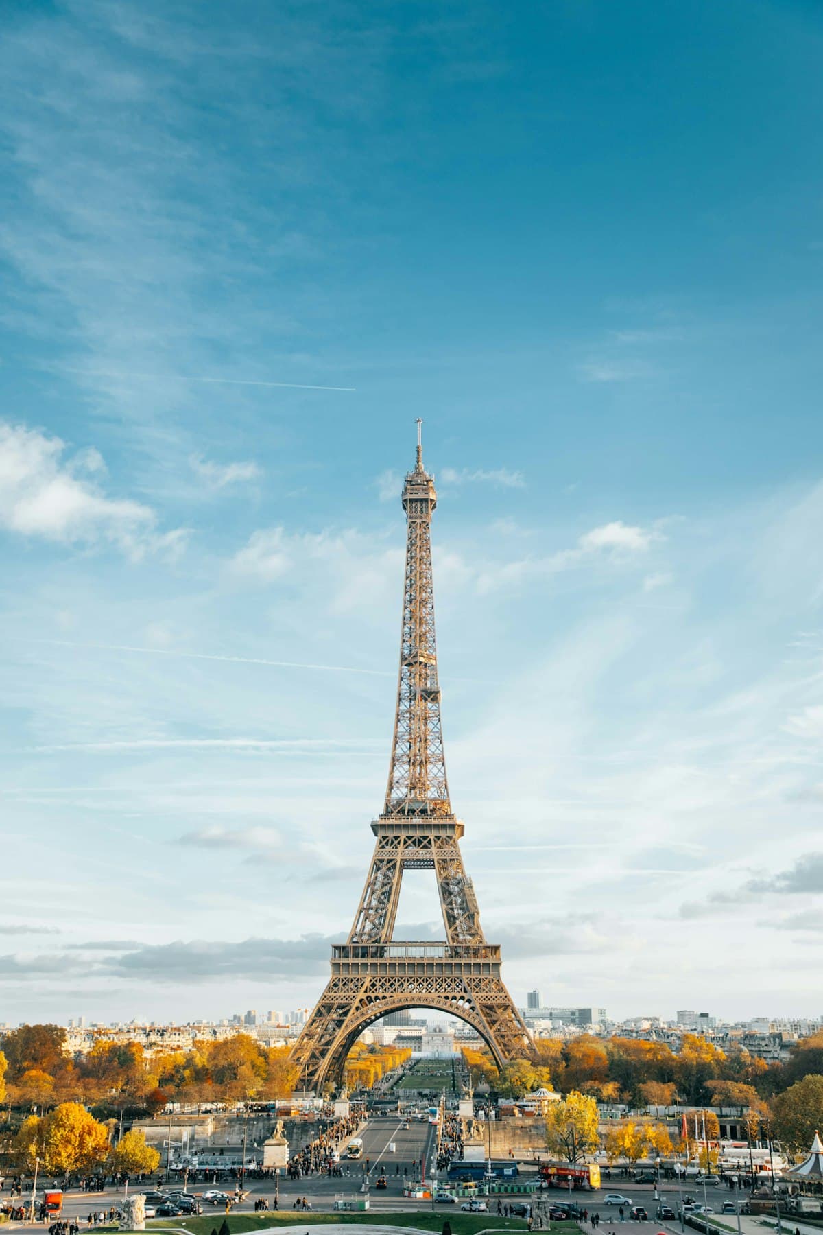 The Eiffel Tower under a blue sky above autumn trees